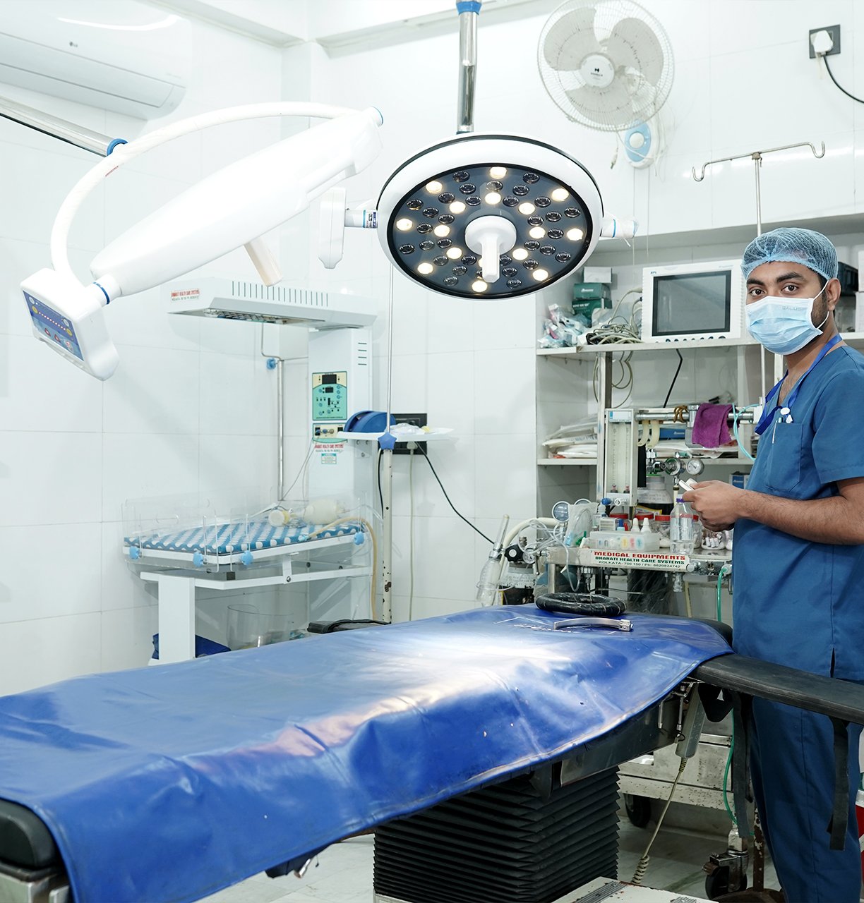 Modern operation theatre setup in a nursing home with surgical lights, equipment, and a healthcare professional.