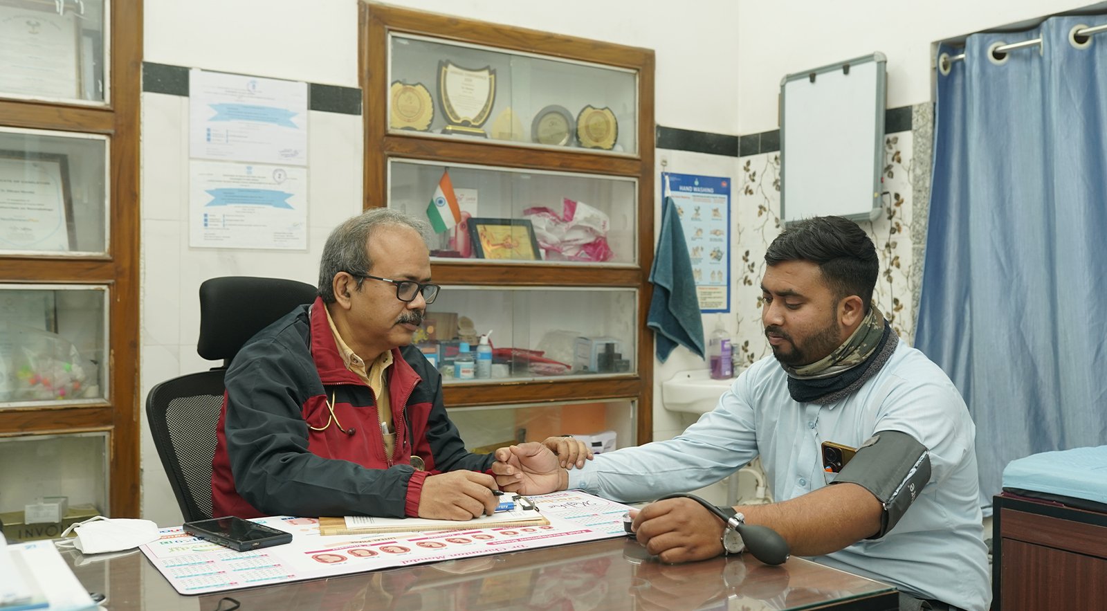Doctor checking a patient’s blood pressure and pulse during a consultation in a nursing home.