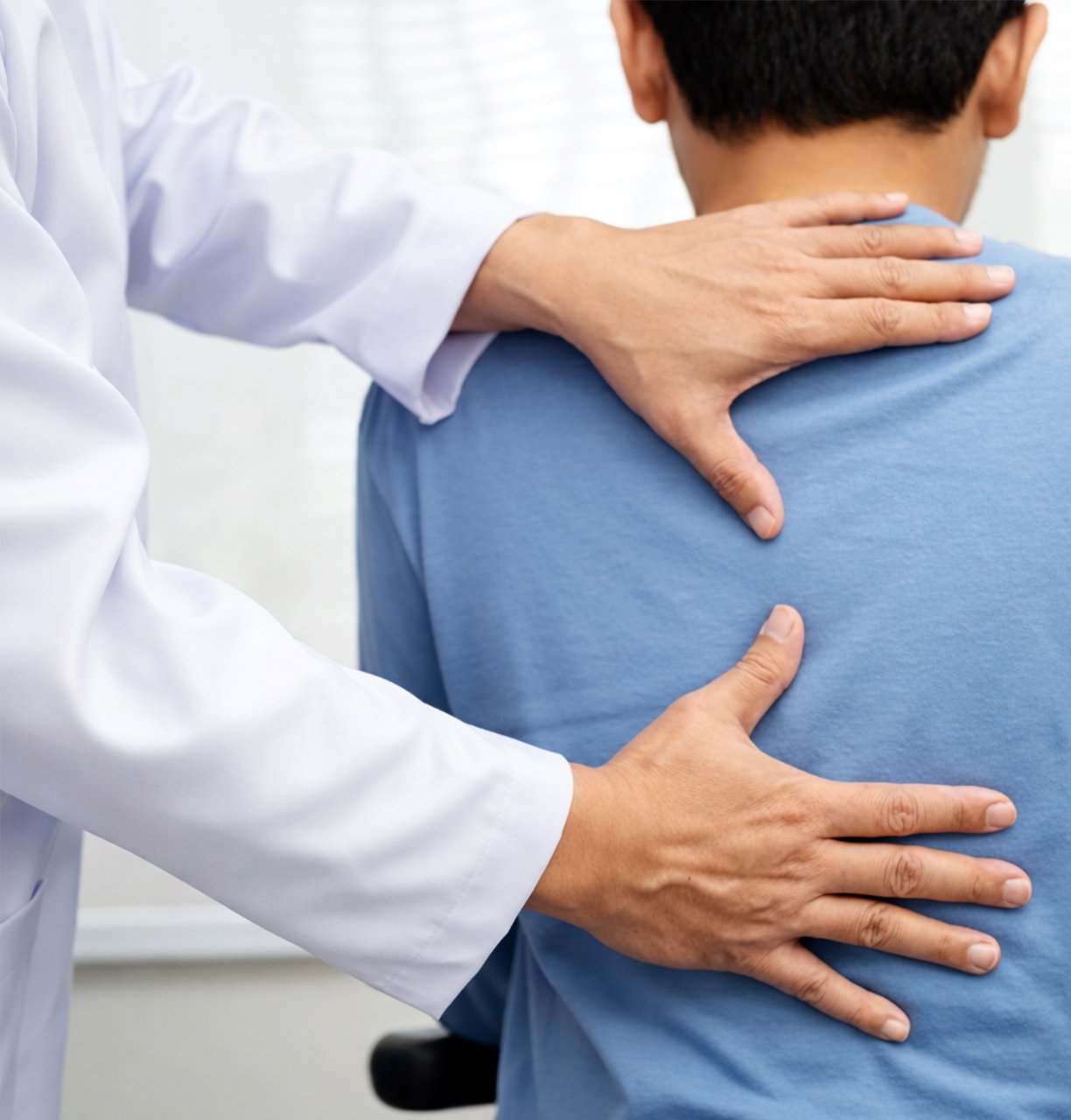 Doctor examining a patient’s back for pain assessment in a nursing home.