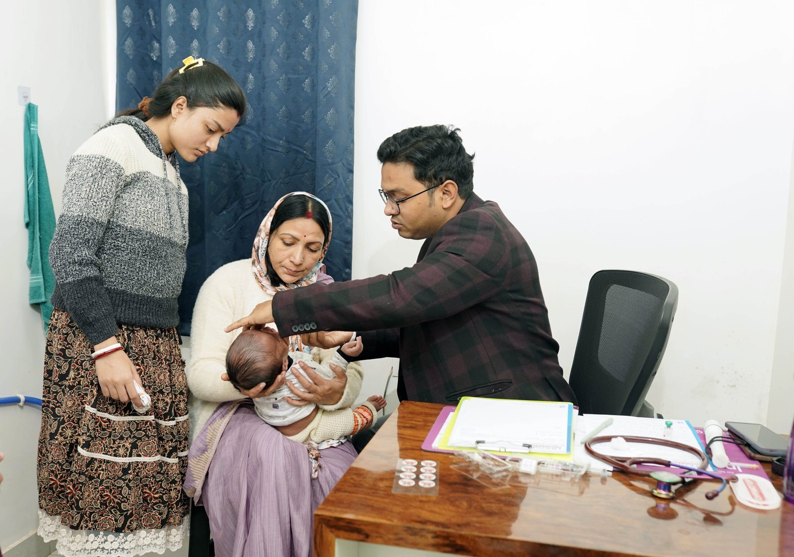 Doctor examining a newborn while family members look on in a nursing home consultation room.