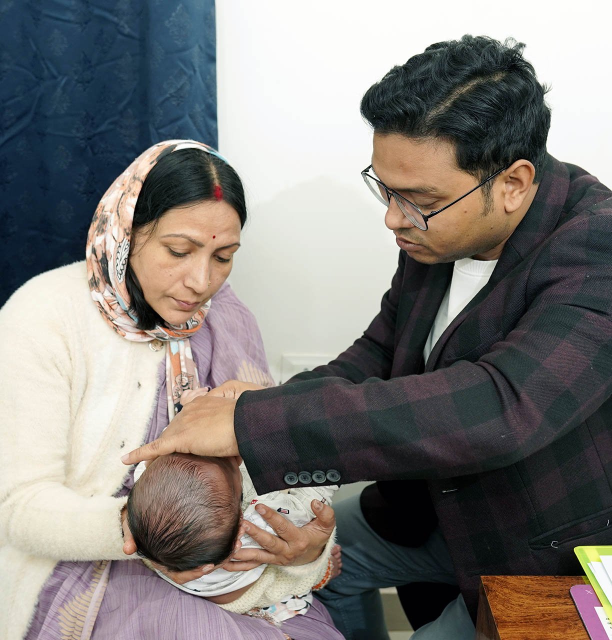 A doctor examining a newborn baby while the mother holds the infant in a nursing home.